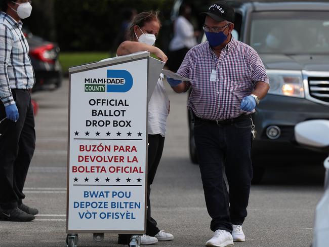 DORAL, FLORIDA - AUGUST 18: Poll workers at the Miami-Dade County Elections Department deposit peoples' mail in ballots into an official ballot drop box on primary election day on August 18, 2020 in Doral, Florida. Voters casts ballots in Miami-Dade to elect Miami-Dades mayor, School Board seats, Miami-Dade state attorney and Judges.   Joe Raedle/Getty Images/AFP == FOR NEWSPAPERS, INTERNET, TELCOS & TELEVISION USE ONLY ==