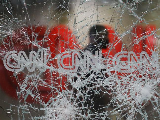 A security guard walks behind shattered glass at the CNN building at the CNN headquarters in the aftermath of a demonstration against police violence in Atlanta. Picture: Brynn Anderson