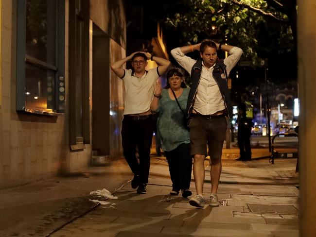 People with their hands on their heads about 10 minutes after midnight as they leave from inside a police cordon after an attack in London. Picture: AP Photo/Matt Dunham