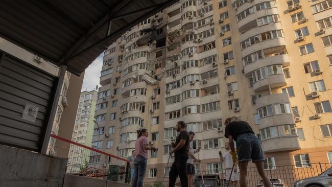 People clean debris in front of a residential building damaged during a Russian air strike. Picture: AFP