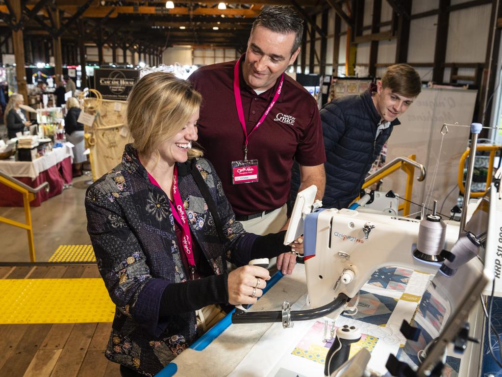 American visitors Janessa Kimball and Nathan Erznoznik of The Grace Company demonstrate quilting machines, as Jackson Cook (right) of The House of Jackson watches, at Craft Alive at the Goods Shed, Saturday, May 21, 2022. Picture: Kevin Farmer