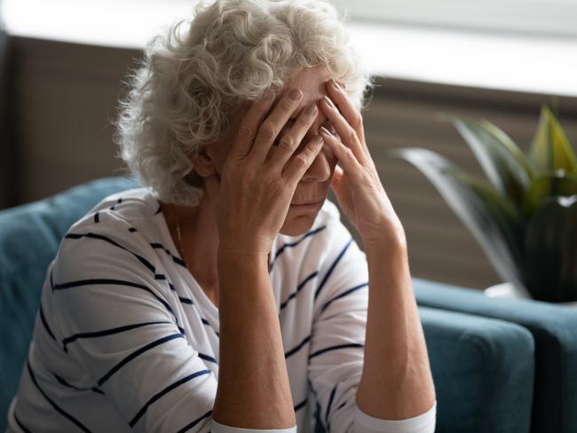 Close up 70s elderly woman sitting on sofa feels desperate crying covered face with hands, senile sickness need help, mental disorder or dementia, does not see way out difficult life situation concept  - Picture iStock