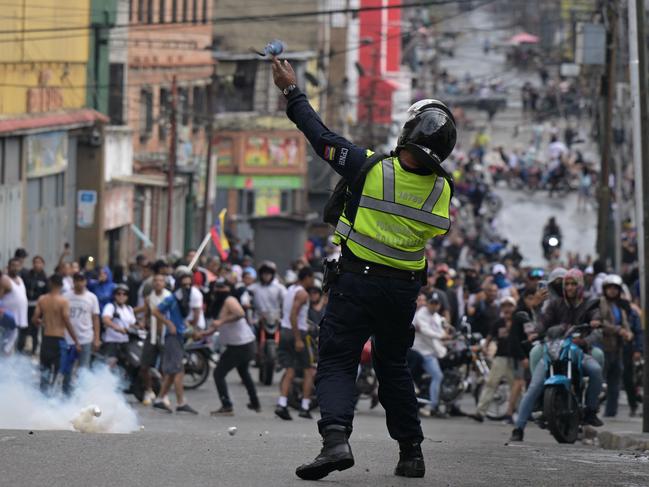 A riot police officer uses tear gas against demonstrators during a protest by opponents of Venezuelan President Nicolas Maduro's government in the Catia neighborhood of Caracas on July 29, 2024, a day after the Venezuelan presidential election. Protests erupted in parts of Caracas Monday against the re-election victory claimed by Venezuelan President Nicolas Maduro but disputed by the opposition and questioned internationally, AFP journalists observed. (Photo by Yuri CORTEZ / AFP)