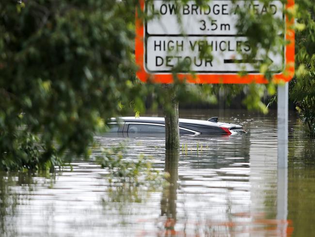 Flood waters pictured on Coronation Drive in inner west Brisbane, with a mostly submerged car. Picture: Josh Woning