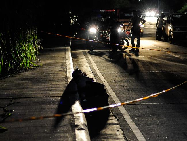 An alleged drug dealer, his hands bound and his head wrapped in tape, lies in the foreground after being shot dead in a Manila street. Picture: Getty Images