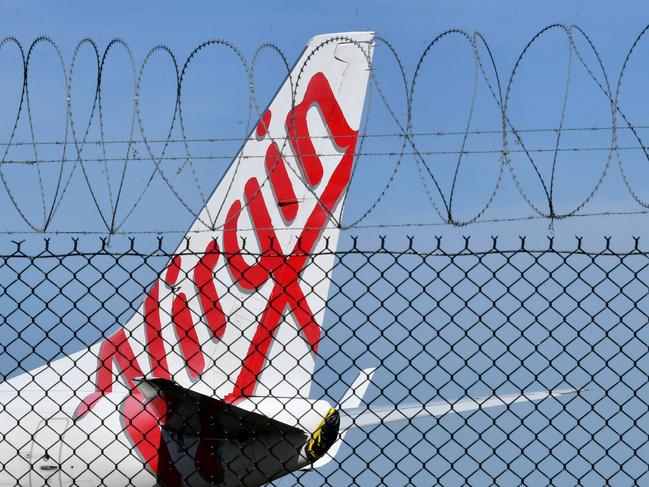 A grounded Virgin Australia aircraft is seen parked at Brisbane Airport in Brisbane, Friday, April 17, 2020. The Australian government has forced airline carriers to cut both their domestic and international flights in order to slow the spread of the coronavirus (COVID-19) disease. (AAP Image/Darren England) NO ARCHIVING