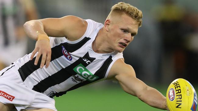 Adam Treloar of the Magpies looks to control the ball.