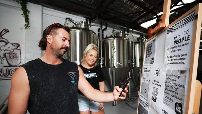 Jesse Waddington checking in to Precinct Brewing Co at Miami under the watchful eye of worker Amy Clements. Picture: Scott Powick