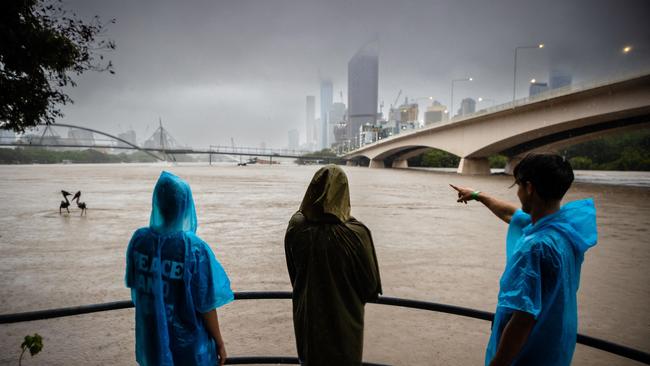 People watch the overflowing Brisbane River amid flooding at South Bank.