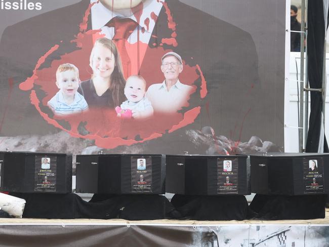 A Hamas militant stands on stage near coffins during the handover of deceased hostages Oded Lifschitz, Shiri Bibas and her two children Kfir and Ariel Bibas, seized during the deadly October 7, 2023 attack, to the Red Cross, as part of a ceasefire and hostages-prisoners swap deal between Hamas and Israel, in Khan Younis in the southern Gaza Strip, February 20, 2025. REUTERS/Ramadan Abed