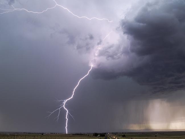 Lightning bolt strike from a thunderstorm with dark clouds and rain.