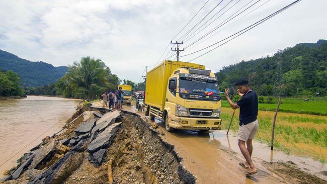 A man guides a truck along an erosion-damaged road in West Sumatra. Picture: AFP