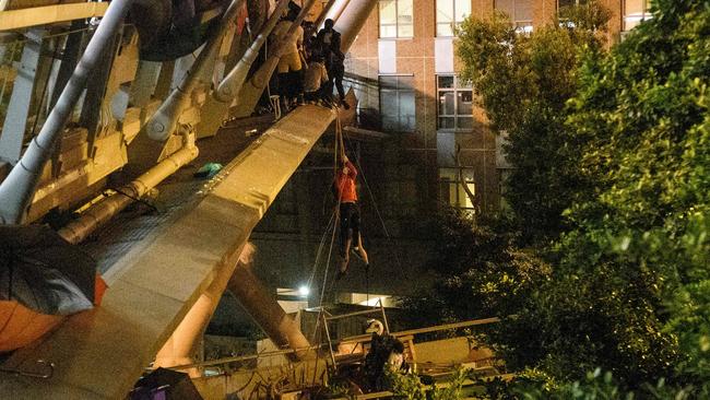 A protester lowers herself down a rope from a bridge to a highway, to escape from Hong Kong Polytechnic University campus. Picture: AFP