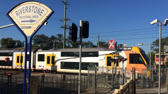 Boom gates down, local traffic stops and a Sydney-bound train is at the level crossing pulling in to the railway station at Riverstone. Picture: John Bilic