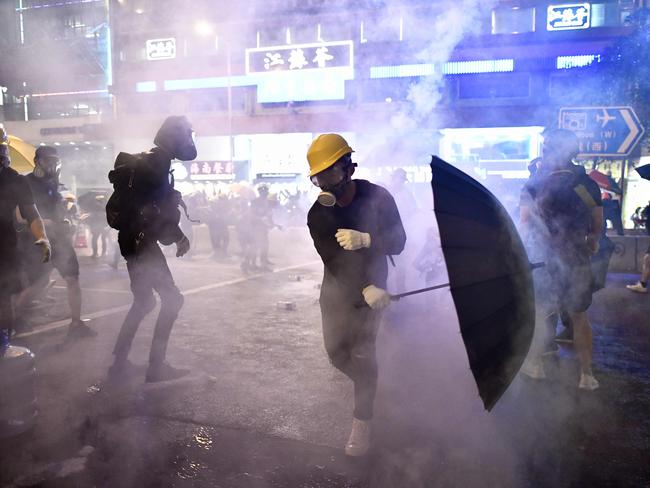 TOPSHOT - Protesters are enveloped by tear gas let off by police during a demonstration against a controversial extradition bill in Hong Kong on July 28, 2019. - Tens of thousands of pro-democracy protesters defied authorities to hold an unsanctioned march through Hong Kong, a day after riot police fired rubber bullets and tear gas to disperse another illegal gathering, plunging the financial hub deeper into crisis. (Photo by Anthony WALLACE / AFP)