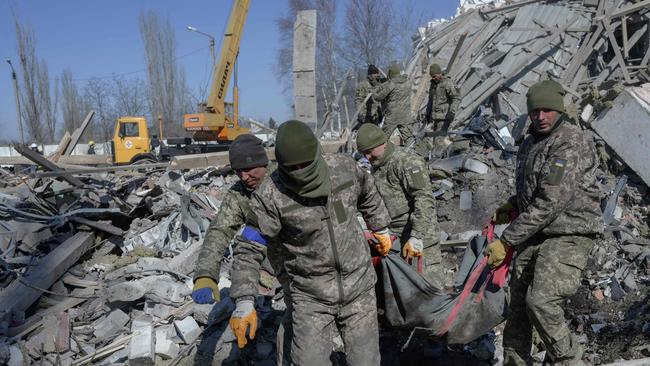 Ukrainian soldiers carry a dead soldier through debris at the military school hit by Russian rockets the day before, in Mykolaiv, southern Ukraine, on March 19. Picture: AFP