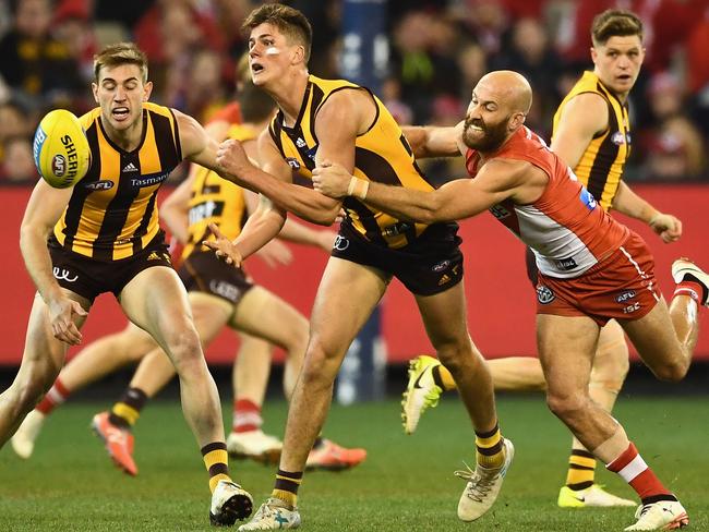 Daniel Howe of the Hawks handballs while being tackled by Jarrad McVeigh.