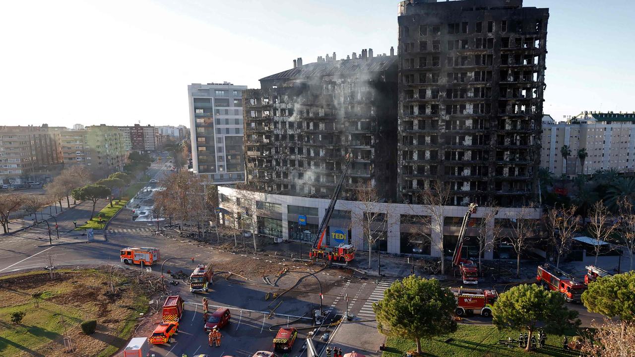 Firefighters inspect the aftermath of a huge fire. (Photo by JOSE JORDAN / AFP)