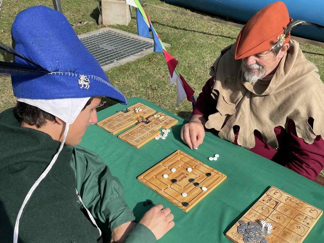 Squire Lachlan and Yoman Roger Greenwood of the Riverbend Medieval Society play Nine Men's Morris at the Fraser Coast Flavours Festival at Seafront Oval on September 1, 2023.