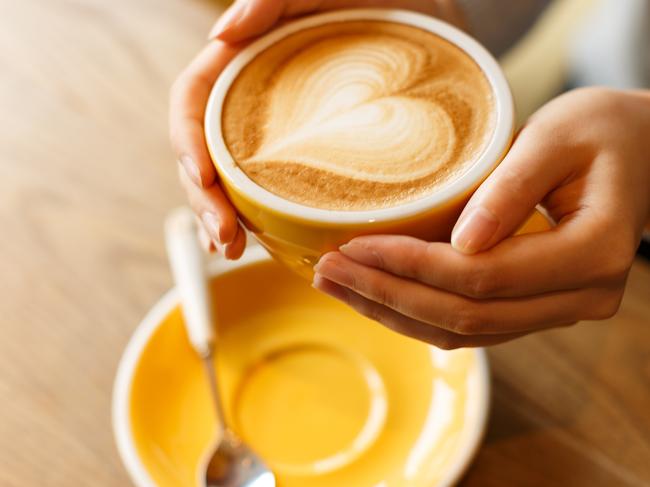 lady's hands hold cup filled with something heart-shaped