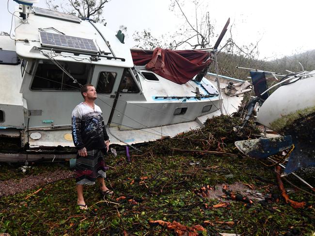 Bradley Mitchell inspects the damage to his uncle's boat after it smashed against the bank at Shute Harbour near Airlie Beach. Picture: AAP Image/Dan Peled