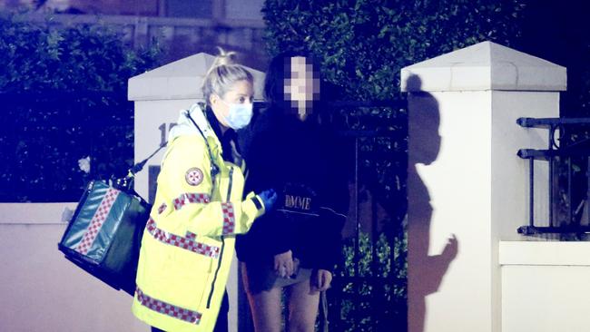 A girl comes out of the house in the care of a paramedic. Picture: Steve Tyson