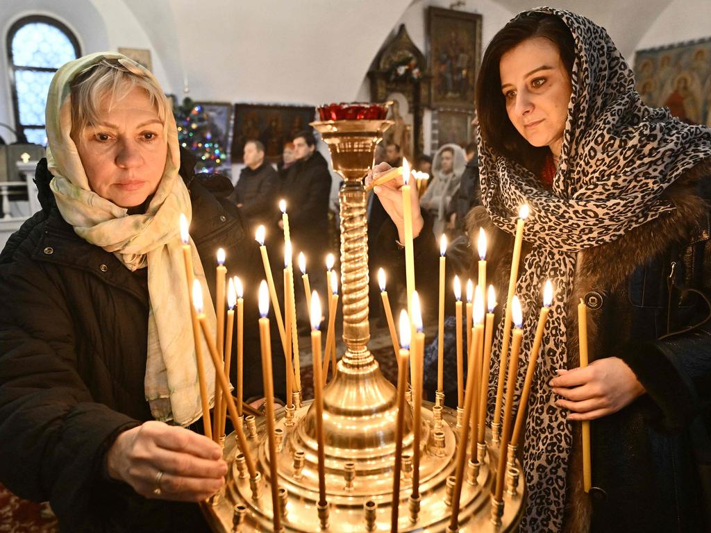 Women light candles during the Christmas service in a church of the Orthodox Church of Ukraine in Kyiv on December 25, 2022, amid the Russian invasion of Ukraine. Picture: AFP