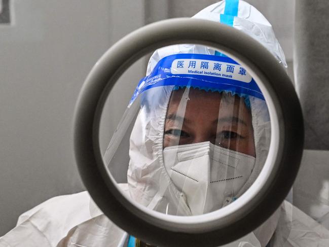 A health worker waits for people to take swab samples to test for the Covid-19 coronavirus in the Jing'an district in Shanghai on December 23, 2022. - China is battling a wave of coronavirus infections that has hit the elderly hard but resulted in only a handful of reported deaths after the government redefined the criteria by which Covid-19 fatalities are counted. (Photo by Hector RETAMAL / AFP)