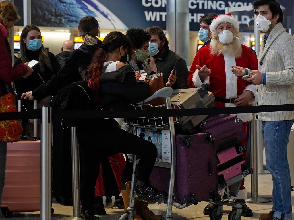 Travellers lined up at London’s Heathrow Airport try to get into the Christmas spirit. Picture: AFP