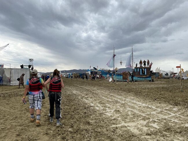 Attendees walk through a muddy desert plain after heavy rains turned the annual Burning Man festival site into a mud pit. Picture: AFP