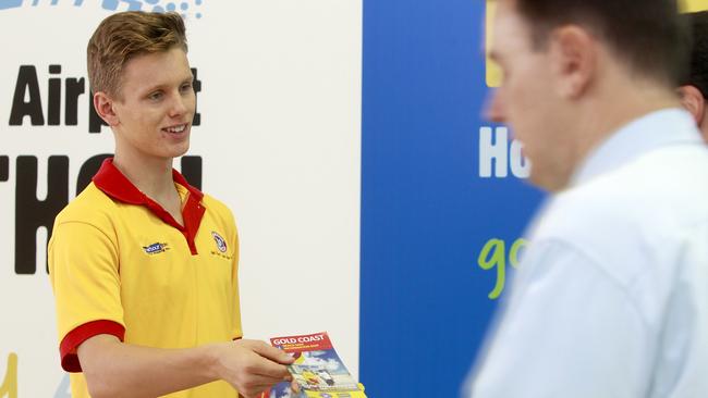 A volunteer surf lifesaver handing out surf safety tips to tourists at Gold Coast Airport.