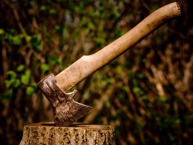 An axe stuck in a piece of wood.