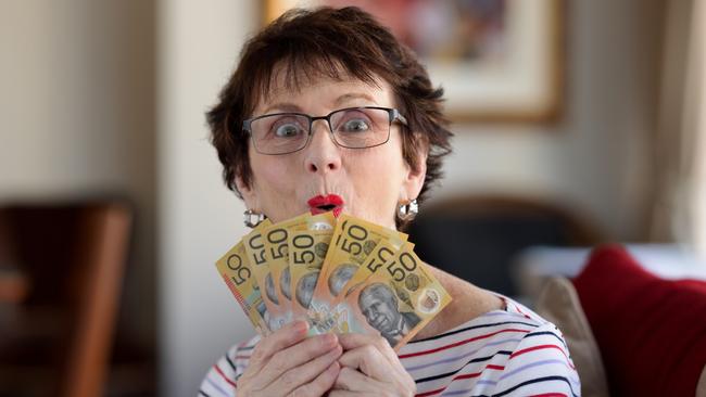 Woman with a surprised expression holding a fan of A$50  notes. Australian money generic banking