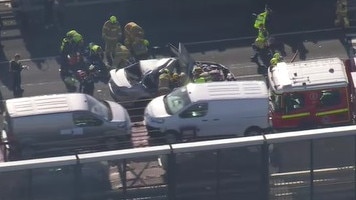 The mangled wreck of a car can be seen on the bridge.