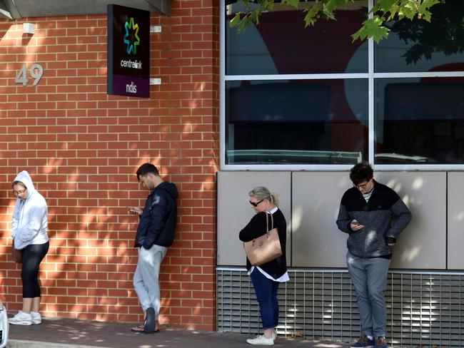 People are seen queuing outside the Centrelink office at Norwood in Adelaide, Monday, March 23, 2020. The federal government has announced two separate economic stimulus packages, including increased access to Centrelink payments designed to help support the Australian economy through the COVID-19 pandemic. (AAP Image/Kelly Barnes) NO ARCHIVING