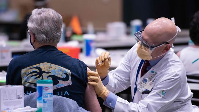 Chief clinical officer John Corman MD at Virginia Mason administers a dose of the Pfizer Covid-19 vaccine at the Amazon Meeting Center in downtown Seattle.