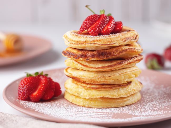 Freshly baked pancakes with strawberries on a natural wood background