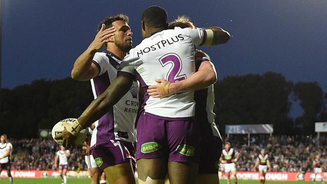 Suliasi Vunivalu celebrates with Storm teammates after scoring a try.