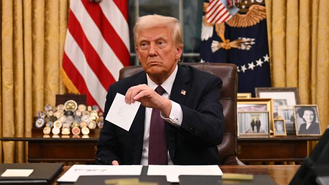 President Donald Trump holds up outgoing President Joe Biden's letter as he signs executive orders in the Oval Office on January 20. Picture: Jim Watson/AFP