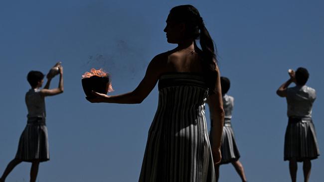 A woman in the role of a priestess holds the Olympic flame after lighting it during the rehearsal of the flame lighting ceremony for the Paris 2024 Olympics Games.