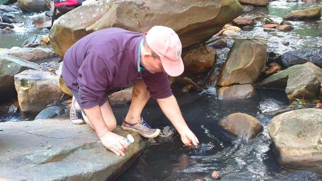 Dr Ian Wright with a handful of black sludge in Camp Gully Creek. He took samples. Picture: Supplied