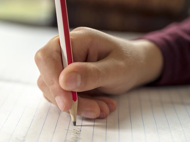 Boy writing in a notepad doing his school work spelling or homework