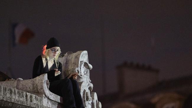 A woman sits on the Monument de la Republique during a protest of centrist incumbent President Emmanuel Macron's apparent defeat of far-right rival Marine Le Pen for a second five-year term.