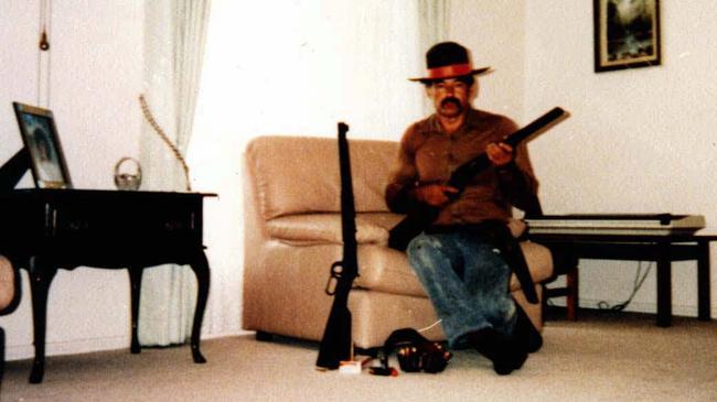 Gun-obsessed Ivan Milat with firearms, ammunition and wearing a cowboy hat on his lounge room recliner in an undated photo. Picture: Supplied