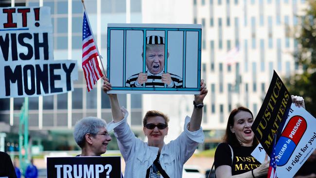 Protestors hold placards before the arrival of former President Donald Trump to New York State Supreme court for the start of the civil fraud trial against him. Picture: AFP.