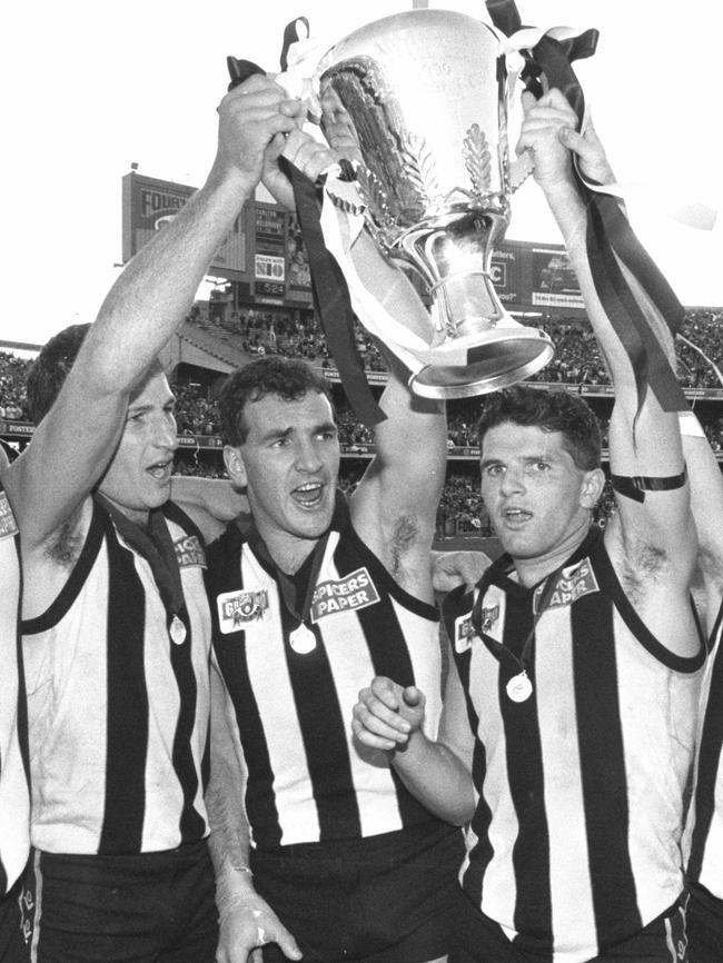 Craig Kelly holds the 1990 AFL premiership cup aloft with Darren Millance and Scott Russell.