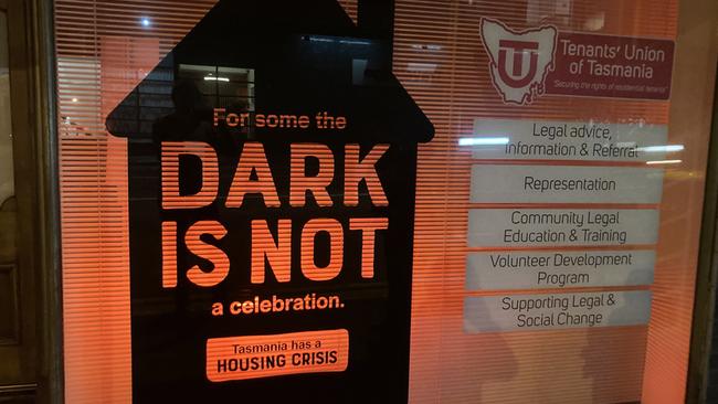 A sign in the window of the Tenants Union of Tasmania office in Hobart lit with red at night. Picture: Tenants Union of Tasmania