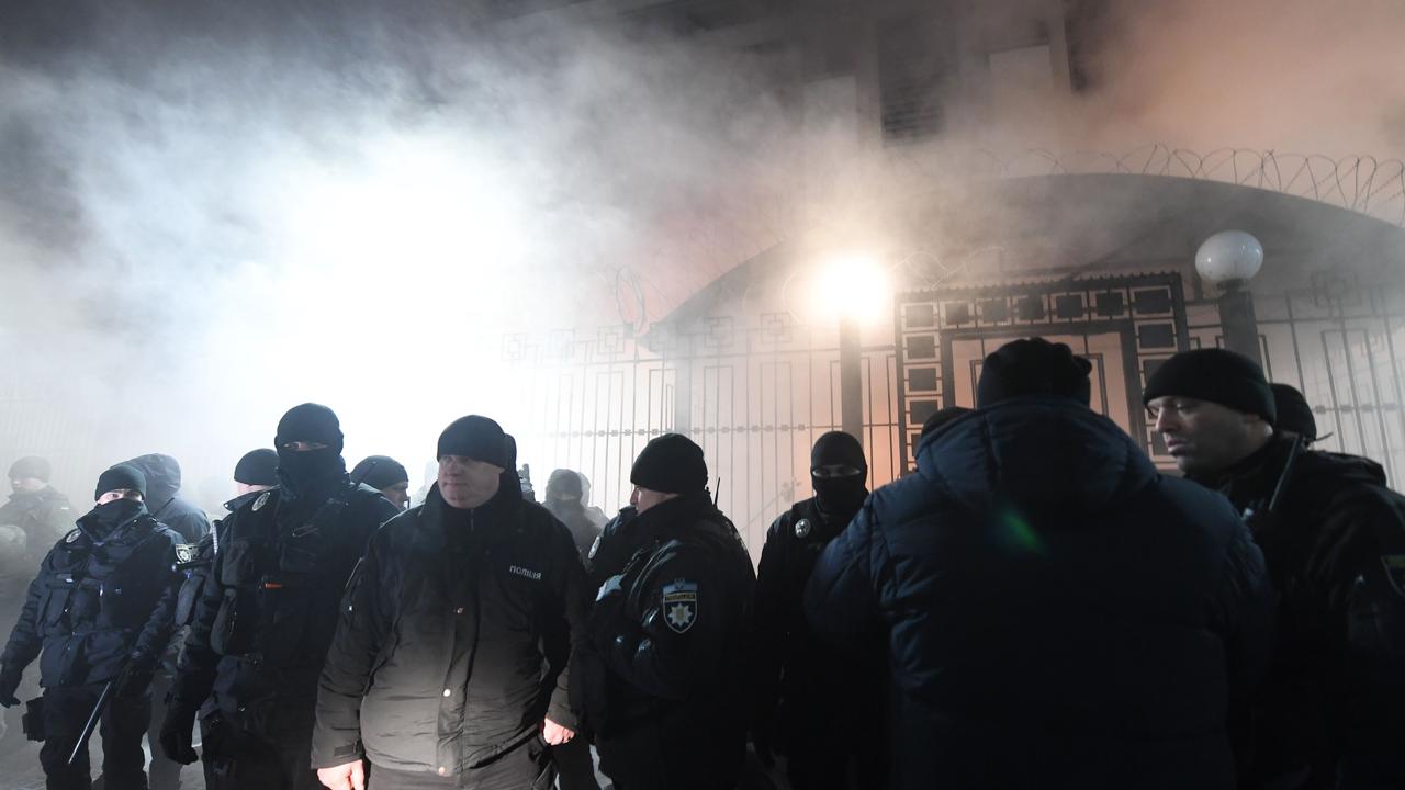 Policemen stand in front of the Russian Embassy in Kiev while smoke from a flare thrown by protesters is seen during a rally, following an incident in the Black Sea Picture: AFP