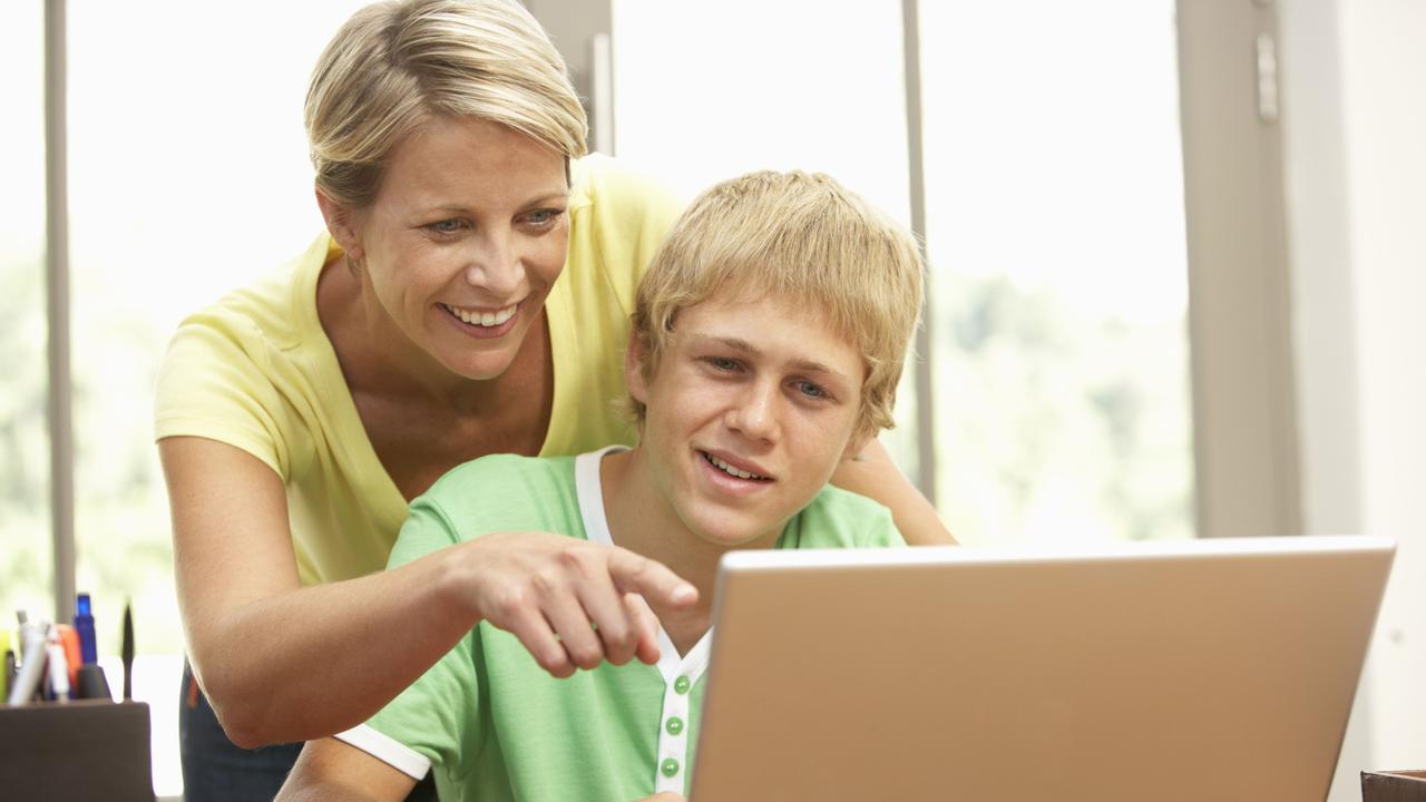 Mother and teenage son using a laptop at home. Parent. Child. Computer. Generic image.