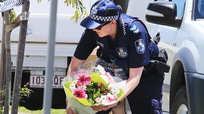 A police officer brings flowers given by a member of the public to lay at the scene. Picture: Tim Marsden